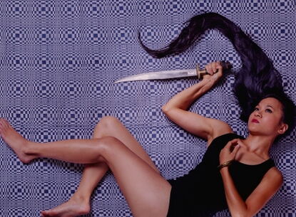 girl holding a long knife with her hair spread out in the same direction as the knife