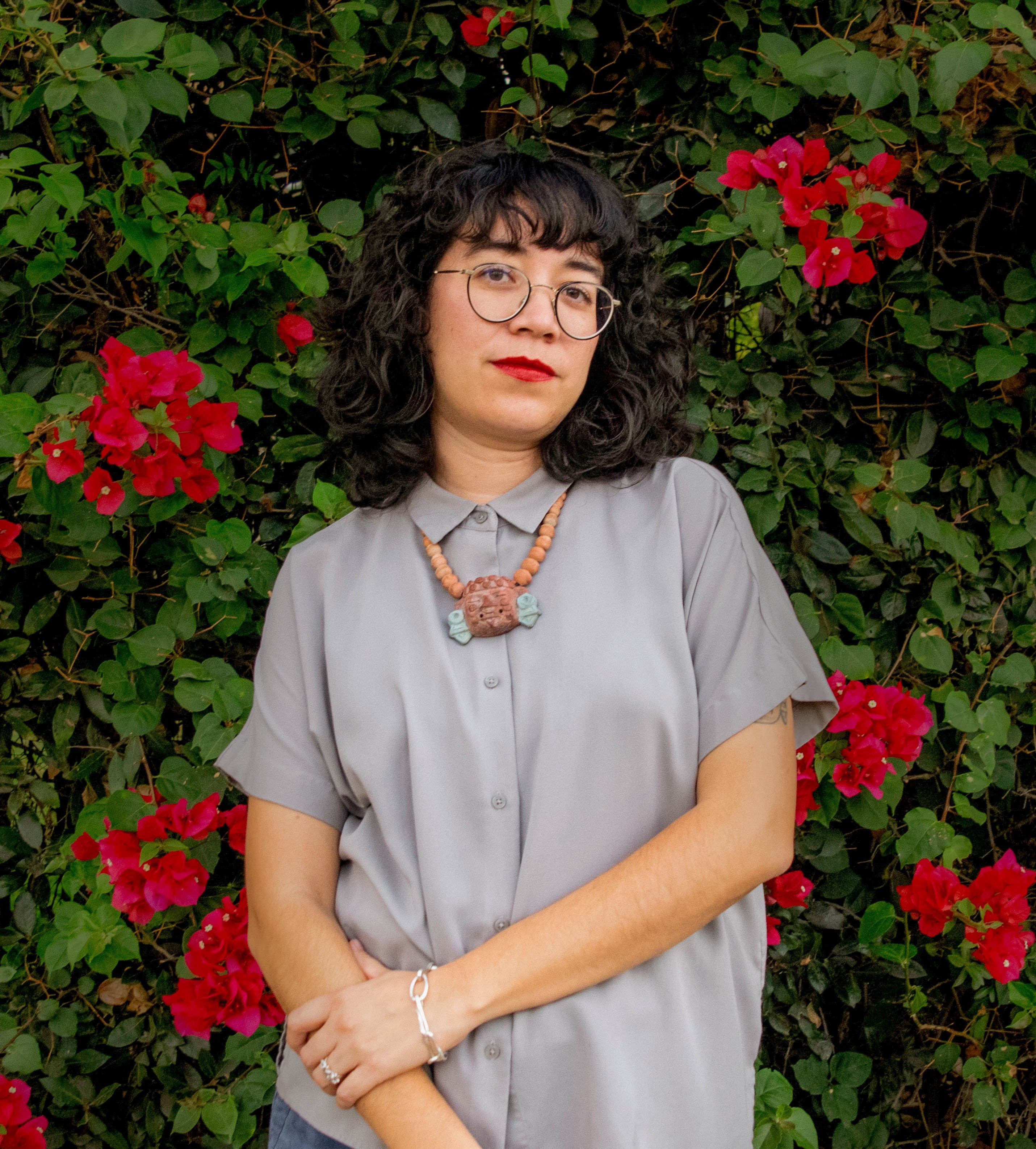 Daniela stands in front of a wall of flowers.