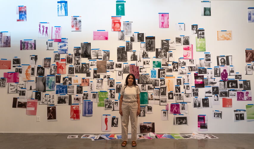 A woman stands in front of drawings