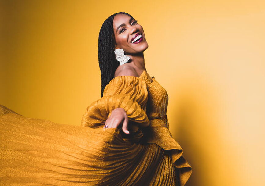 A woman in a yellow dress, smiling.