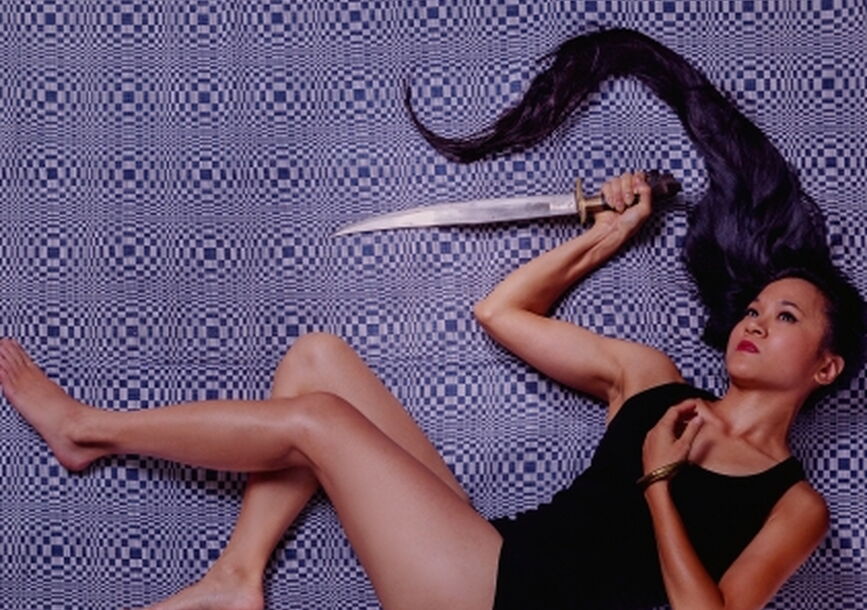 girl holding a long knife with her hair spread out in the same direction as the knife