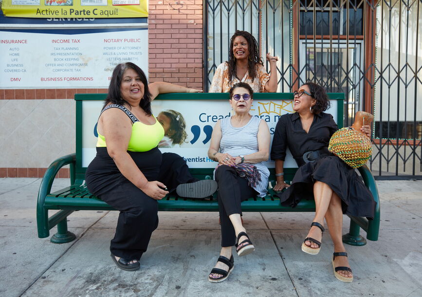 Four people gather around a bench.