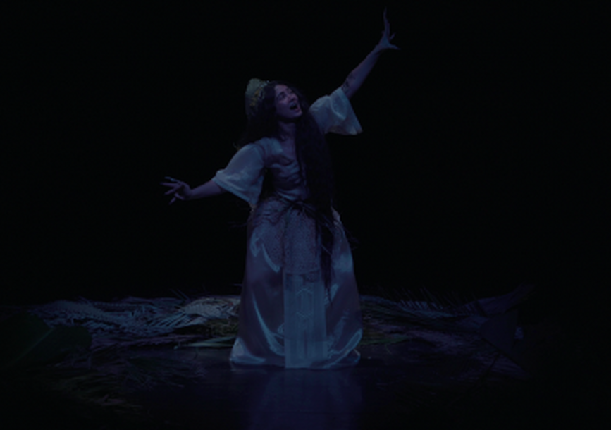 performer in white gown pointing up to the sky