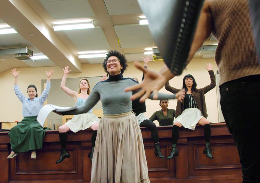 A group of people raise their hands and smile.