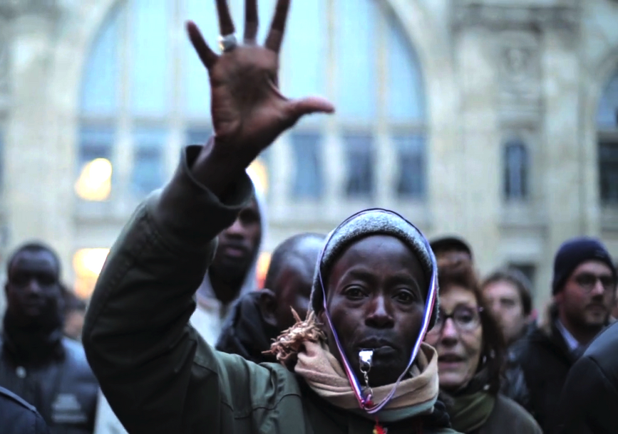 A person stands in a crowd with their hand raised.