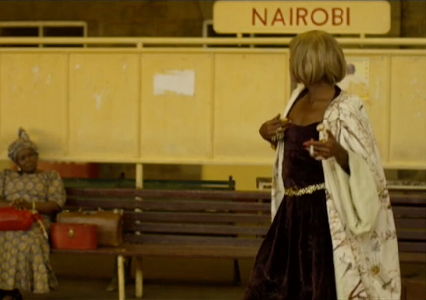 A person with blonde hair faces away at a station.