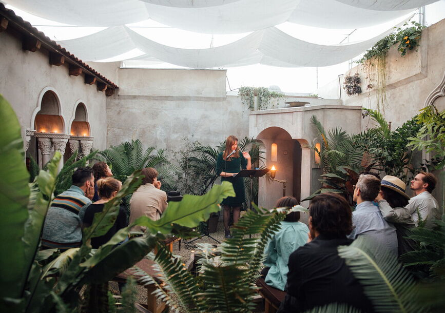 An audience watches a person speak at a podium. 