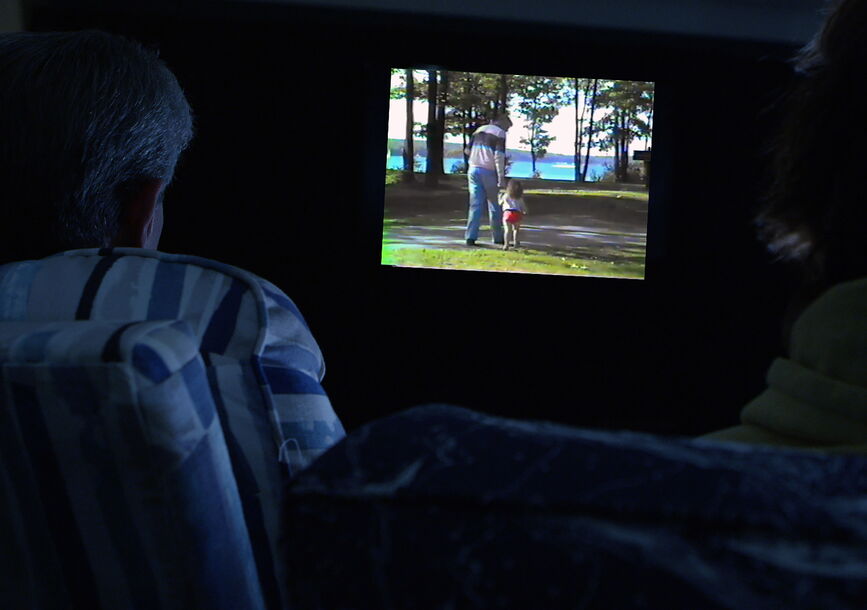 Two people watch television in darkness.