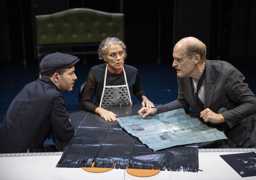 Three people gather around a table.