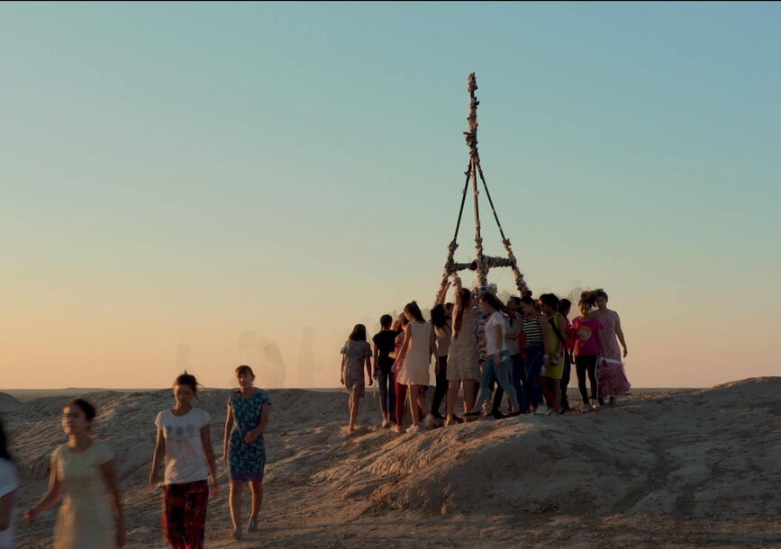People circle around a wooden structure.