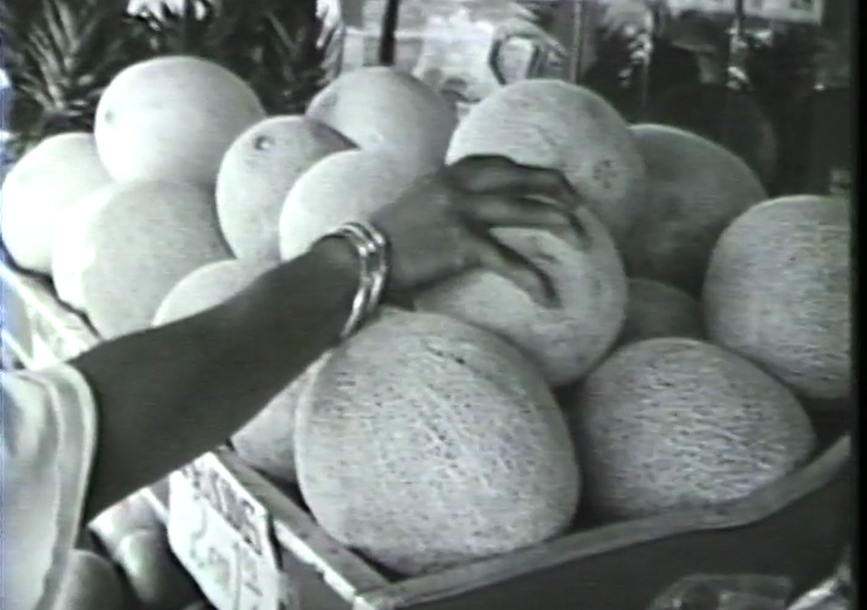 A hand grabs a fruit from a basket.