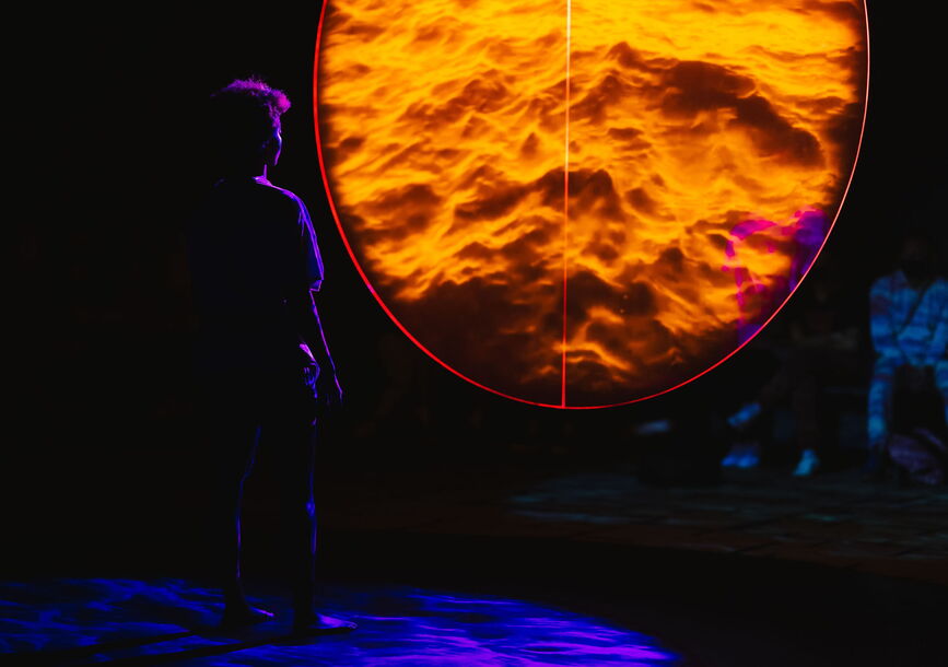 A person stands next to an orange circle.