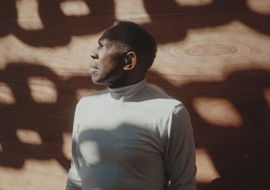 Charles faces away while leaning against a wall.