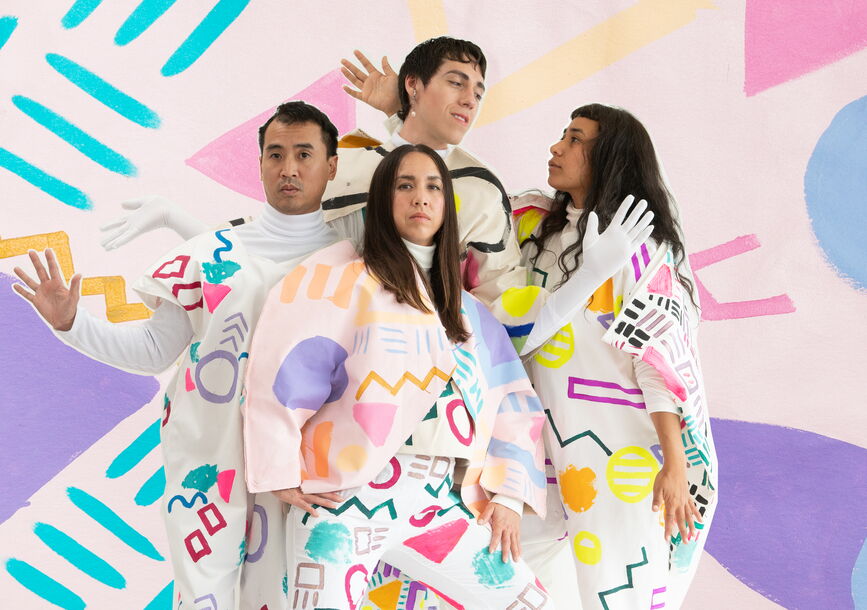 Four people posing with colorful and geometric costumes.