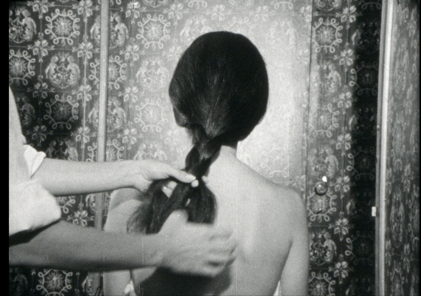 Hands braid a person’s hair.