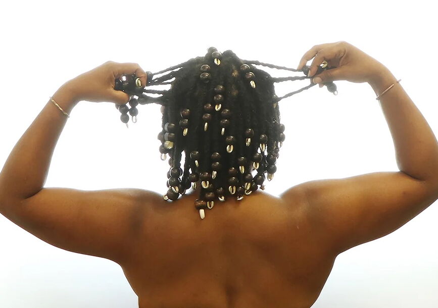 A person lifts their hands to hold their braids.