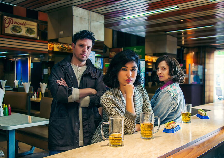 1 man and 2 women at a table staring on camera