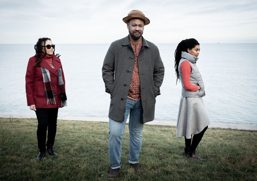 photo of 3 musicians standing in scenic background with grass and then the ocean