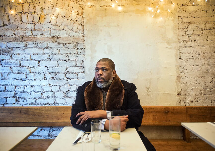 man in coat sitting at a table staring to the right