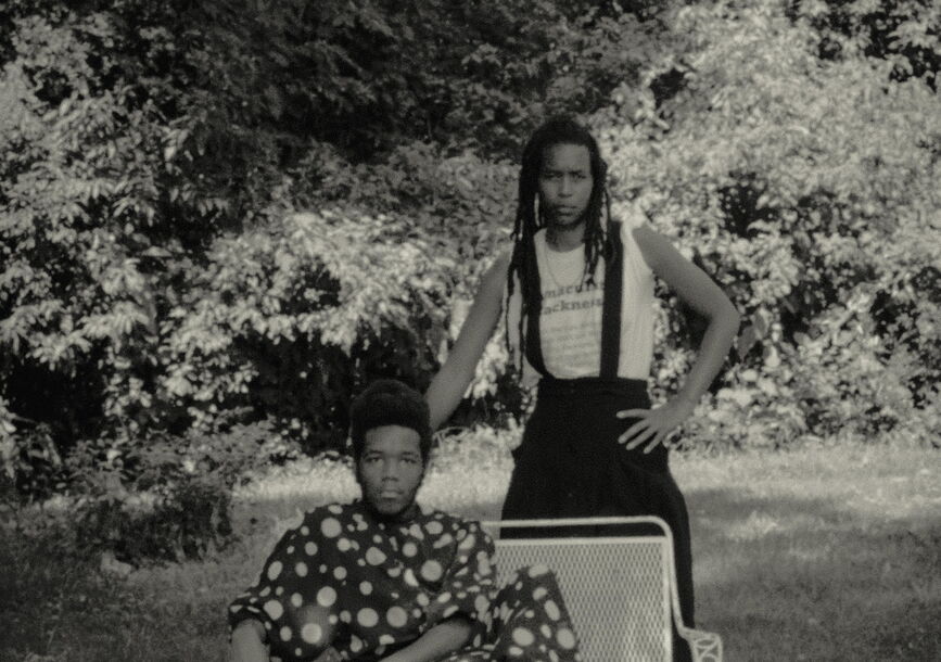 man sitting and a woman standing next to him posing for a photo