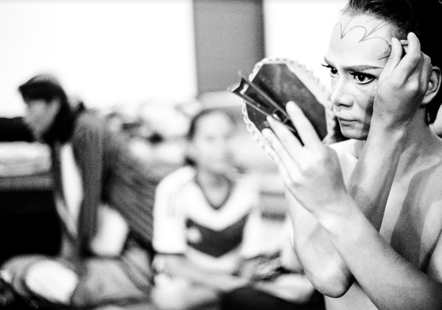 performer putting show make up on with a handheld mirror 