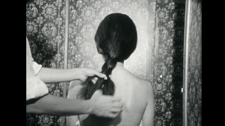 Hands braid a person’s hair. 