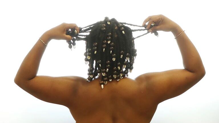 A person lifts their hands to hold their braids.