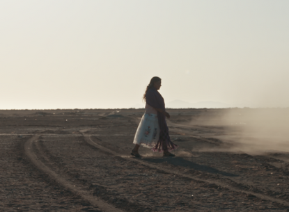 A woman walking across a desert.