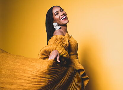 A woman in a yellow dress, smiling.