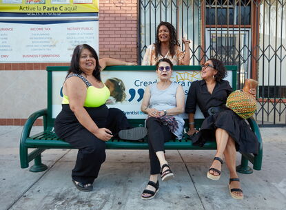 Four people gather around a bench.