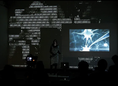 A person stands in front of projected images.