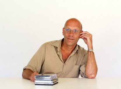 Geert leans to his left while sitting at a table.