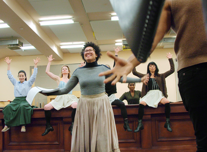 A group of people raise their hands and smile.