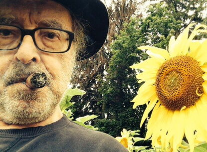 Jean-Luc is side by side with a sunflower.