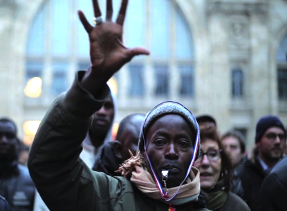 A person stands in a crowd with their hand raised.