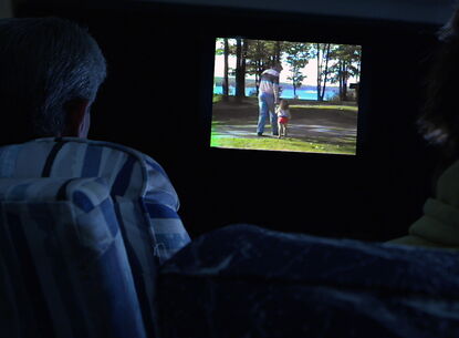 Two people watch television in darkness.