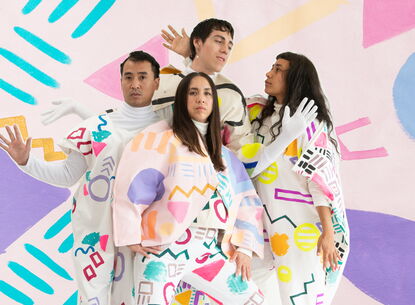 Four people posing with colorful and geometric costumes.