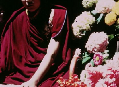 A person sits next to flowers.