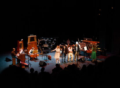 Musicians stand on stage with instruments.