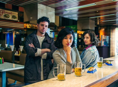 1 man and 2 women at a table staring on camera