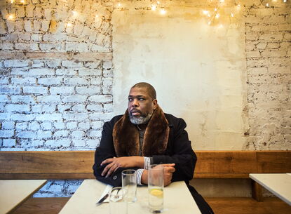 man in coat sitting at a table staring to the right