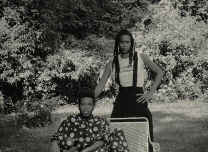 man sitting and a woman standing next to him posing for a photo