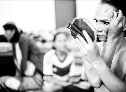 performer putting show make up on with a handheld mirror 