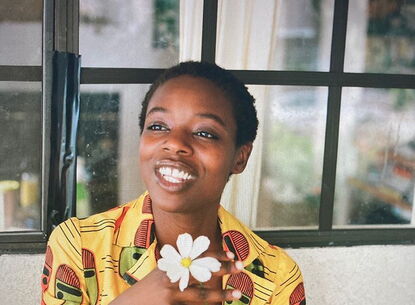 woman in floral designer jacket, smiling and sitting at a table